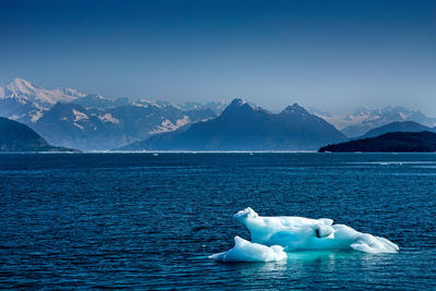 Scenic view of sea and snowcapped mountains against sky