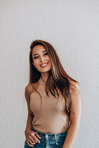 Portrait of a smiling young woman against wall