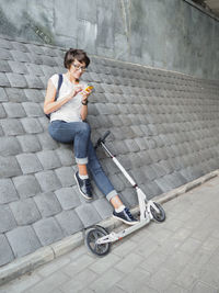 Smiling woman texting on smartphone after riding kick scooter. .eco-friendly urban transport