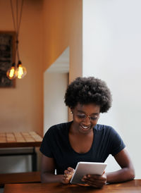 Young woman using phone while sitting on table