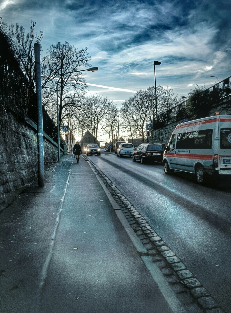 transportation, car, land vehicle, street, road, sky, mode of transport, the way forward, building exterior, street light, tree, built structure, city, architecture, cloud - sky, road marking, diminishing perspective, city street, vanishing point, bare tree