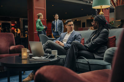 Male and female entrepreneurs discussing business strategy while sitting in hotel lounge