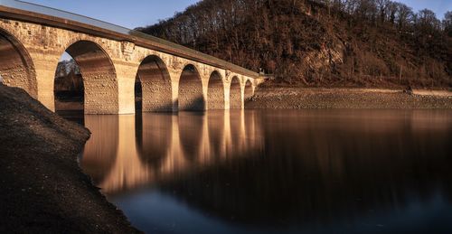 Arch bridge over river against sky