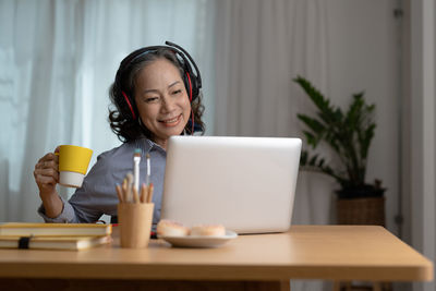 Portrait of young woman using laptop while sitting on table