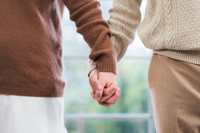 Midsection of couple holding hands