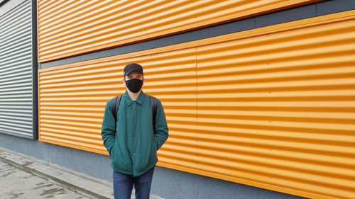 Rear view of man standing against yellow wall