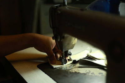 Cropped image of hand sewing fabric on machine