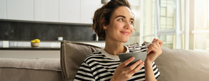 Young woman using mobile phone while sitting on sofa at home