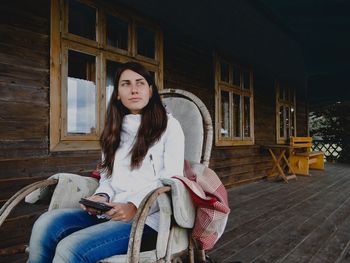 Young woman relaxing outside house on chair