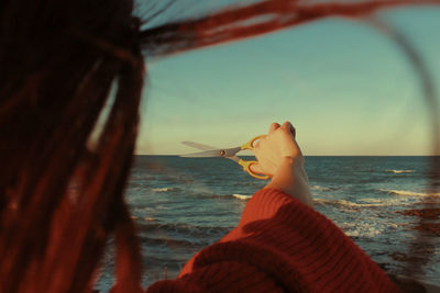 Midsection of person on beach against sky