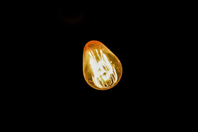 Low angle view of illuminated light bulb against black background