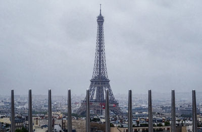 Communications tower in city against sky