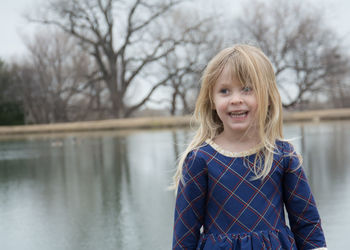 Portrait of smiling girl standing against trees