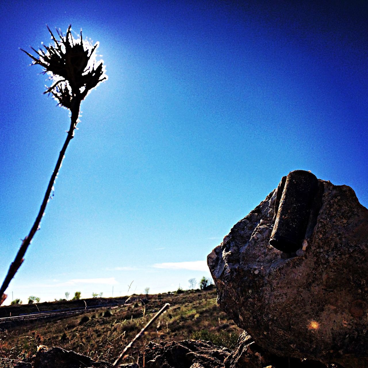 clear sky, blue, copy space, landscape, tranquility, nature, low angle view, field, tranquil scene, sunlight, rock - object, sky, hill, tree, built structure, abandoned, day, non-urban scene, outdoors, no people