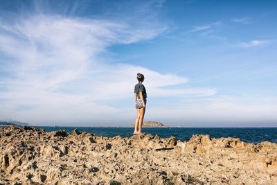 Rear view of shirtless man standing at beach against sky