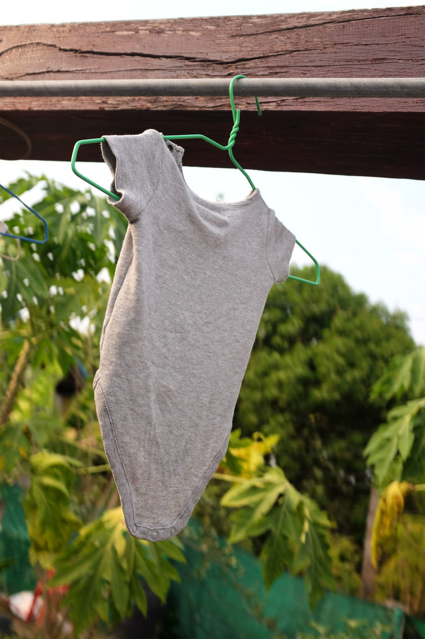 CLOSE-UP OF CLOTHES DRYING ON CLOTHESLINE AGAINST PLANTS
