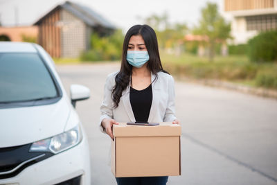 Portrait of young woman standing on car