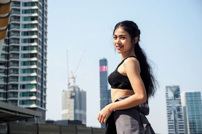 Smiling woman standing against buildings in city
