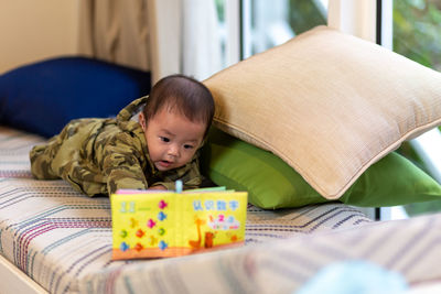 High angle view of cute baby boy sitting on bed at home