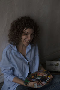 Portrait of a smiling young woman against wall at home