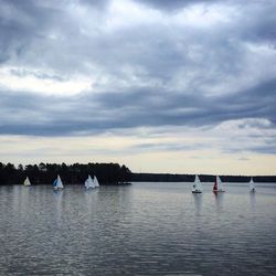 Boats in sea against cloudy sky