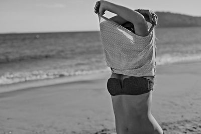 Midsection of woman at beach against sky