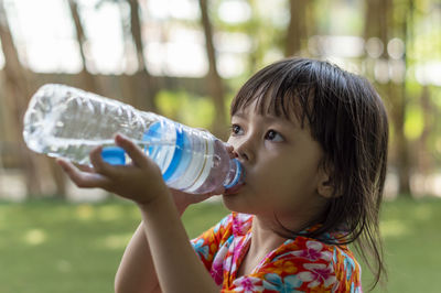 Close-up of cute girl drinking water while standing outdoors