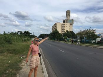People walking on road against cloudy sky