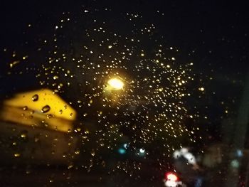 Close-up of raindrops on illuminated street at night