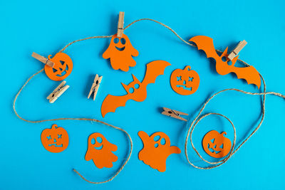 Preparation for holiday. decorations for halloween on a rope with pins on a blue background.