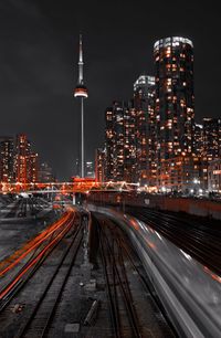 High angle view of illuminated railroad tracks amidst buildings in city at night