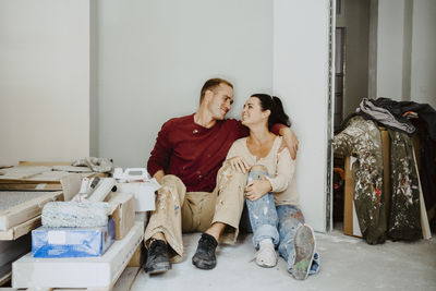 Romantic couple sitting together in room while renovating home