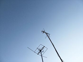 Low angle view of silhouette telephone pole against clear blue sky