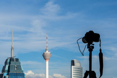 Low angle view of communications tower against cloudy sky