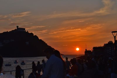 Silhouette people in city against sky during sunset