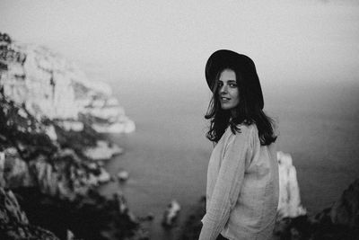 Portrait of smiling young woman wearing hat standing against sky