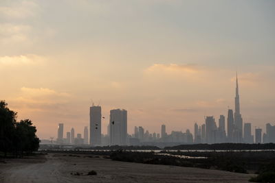 Modern buildings in city against sky during sunset