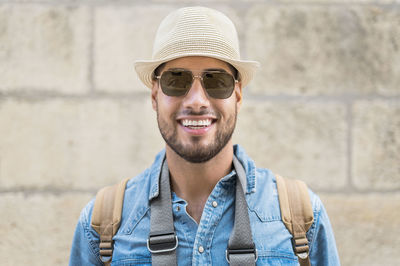 Portrait of young man wearing hat against wall