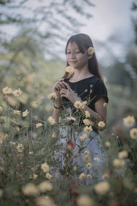 Young woman looking away while standing on field