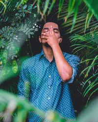 Man with eyes closed standing against plants
