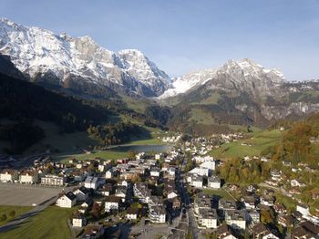 Aerial view of townscape by mountains against sky