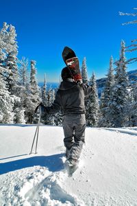 Rear view of man with snowboard walking on snowcapped mountain