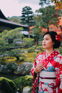 Young woman wear kimono standing against plants