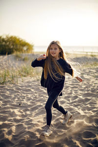 Portrait of a girl with long hair run on a sandy beach in a black leather jacket