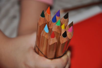 Close-up of hand holding multi colored pencils