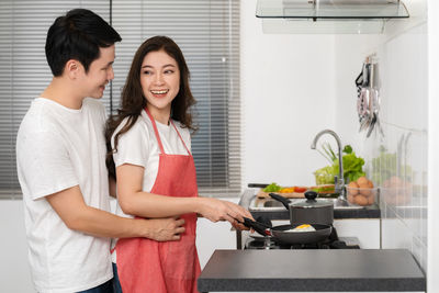 Portrait of female friends using mobile phone while standing in kitchen