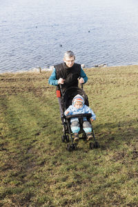 Grandfather pushing granddaughter stroller at lakeshore