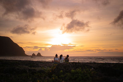 People on beach against sky during sunset