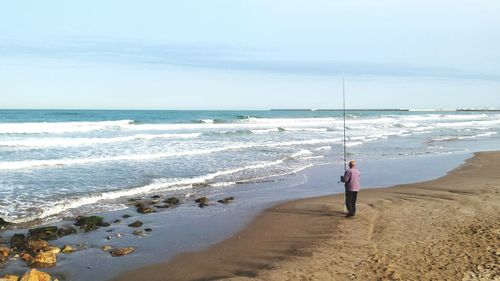 Scenic view of beach against sky wit man fishing