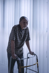 Disabled man walking by blinds with walker 